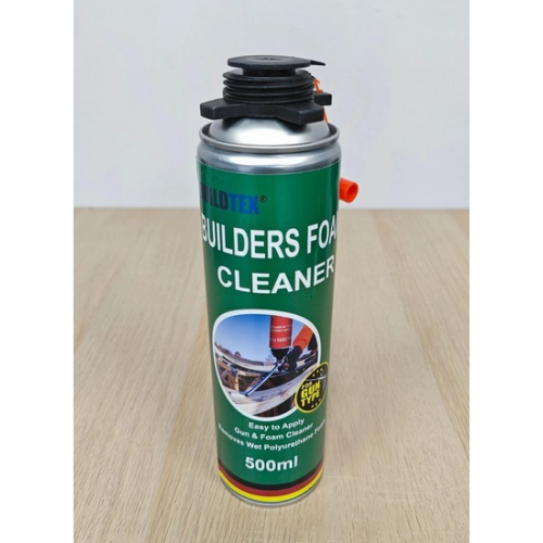 A 500ml can of Builder Foam Cleaner with a green label, silver metal body, black nozzle cap, and a small red valve, standing on a light wood surface against a white background.