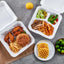 Assorted food items including a burger, fries, and salad in takeout containers on a gray surface.