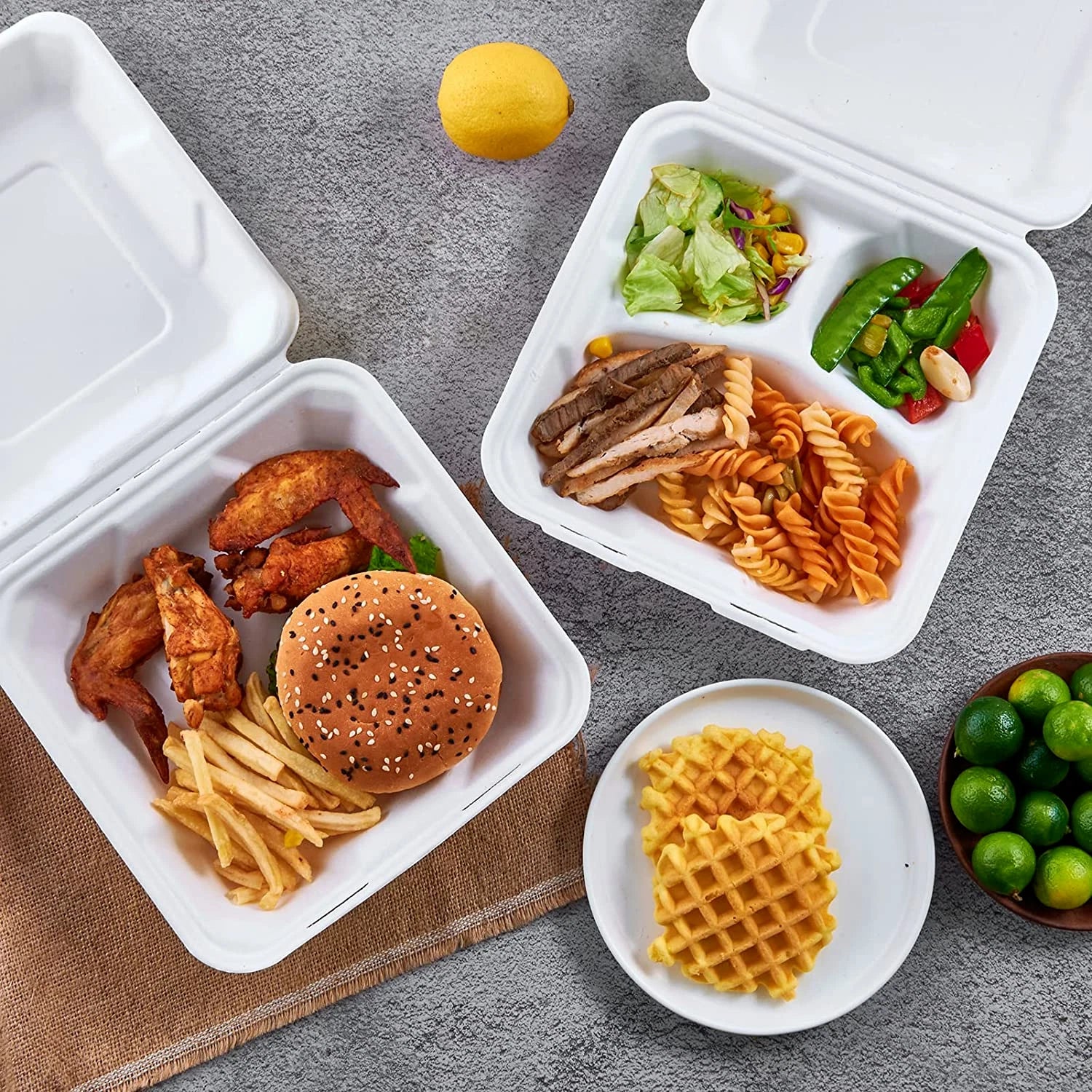 Assorted food items including a burger, fries, and salad in takeout containers on a gray surface.