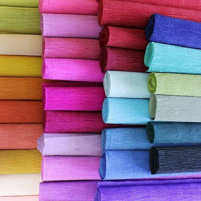 Assorted rolls of crepe paper in various colors neatly stacked together.