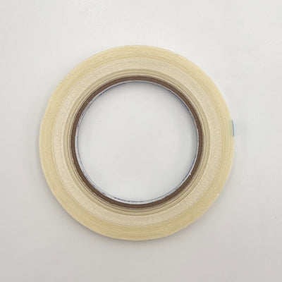 A roll of light beige masking tape on a plain white background.