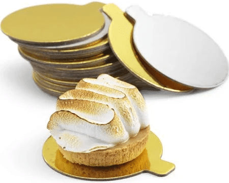 Small dessert with meringue on a gold plate, surrounded by additional gold plates.