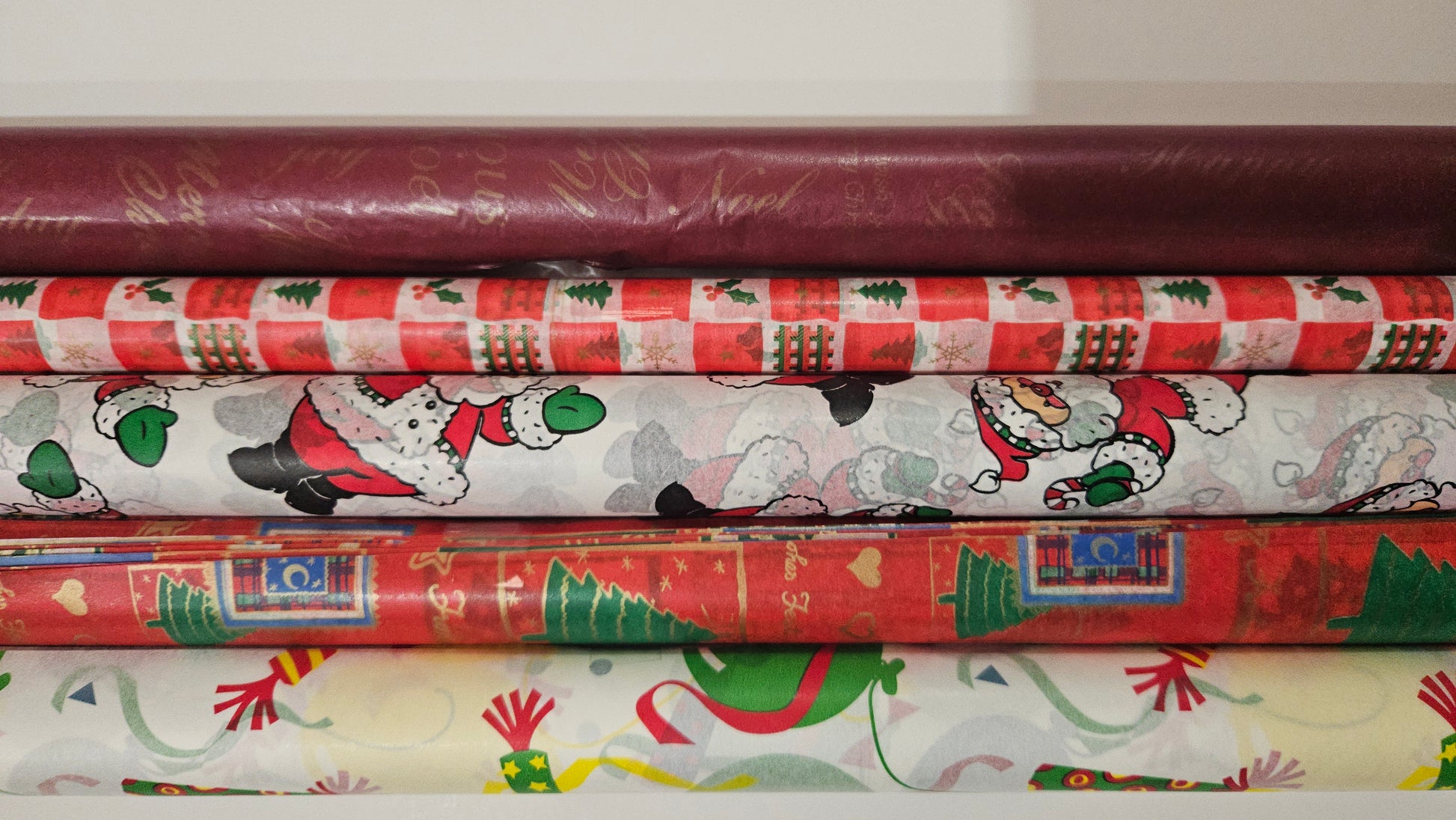 Stack of Christmas-themed wrapping paper rolls on a white background