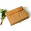 A stack of brown kraft envelopes displayed on a surface with a sprig of herbs to the side.