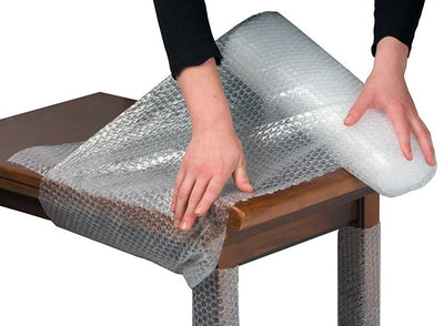 A person wrapping a table with bubble wrap